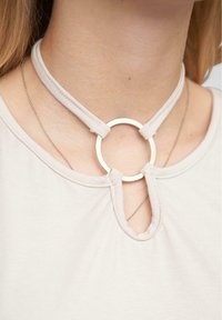 Choker náhrdelník z jemnej béžovej látky s okrúhlym strieborným akcentom vpredu, s dizajnom v tvare kľúčovej dierky.