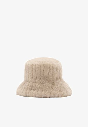 Chapeau seau en fausse fourrure beige avec une texture douce et des lignes verticales cousues, conçu pour la chaleur et le style.