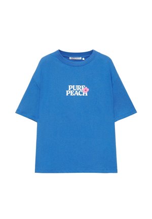 Blue short-sleeve t-shirt with white "PURE PEACH" text and a small pink flower graphic on the chest.