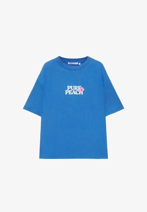 T-shirt blu a maniche corte con scritta bianca "PURE PEACH" e una piccola grafica di fiore rosa sul petto.