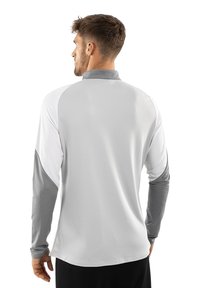Langarm sportshirt in lichtgrijs met donkere grijze accenten. Voorzien van een kraag en contrasterende witte mouwen. Vochtregulerende stof.