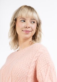 Világos rózsaszín kötött pulóver, kábelmintázattal, kerek nyakkal és laza szabással. Puha tapintású, látható varrási részletekkel.