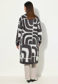 Langer, gemusterter Cardigan in Dunkelgrau und Hellgrau mit abstrakten Formen. Hergestellt aus weichem, strukturiertem Stoff mit langen Ärmeln.