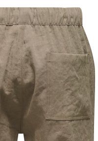 Beige linnedbukser med elastisk talje og en enkelt påsyet lomme på bagsiden, lavet af en tekstureret, let krøllet stof.