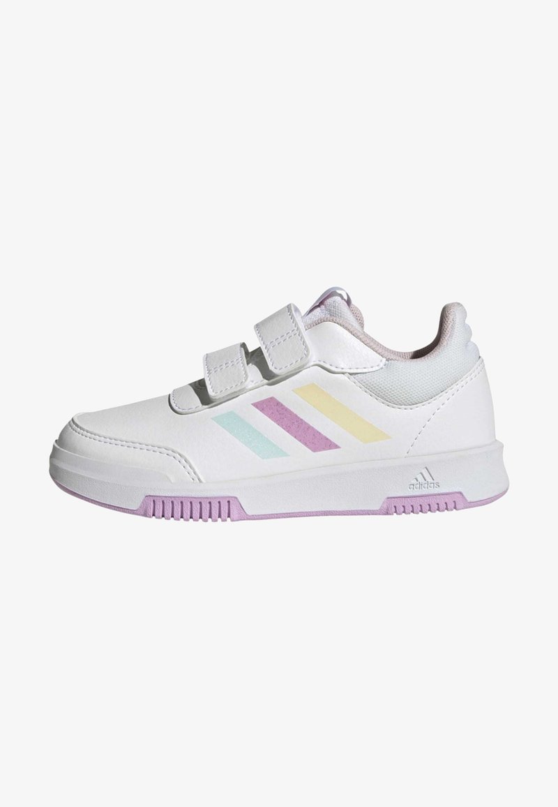 Zapatilla deportiva blanca con dos correas de velcro, que presenta rayas diagonales en tonos pastel de azul, morado y amarillo. Suela texturizada en morado y blanco.
