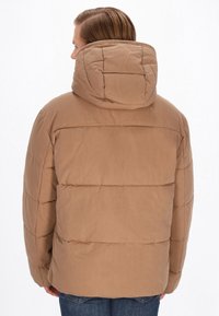 Brun pufferjakke med hætte, der har et quiltet design og vandret syninger. Stoffet ser glat ud med en mat finish.