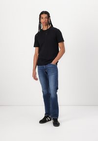 Svart t-skjorte med korte ermer, blå rette jeans og svarte joggesko. Glatt stoff, enkelt design, avslappet passform.