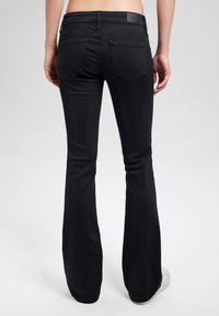 Mustat leveälahkeiset farkut, jotka on valmistettu denimistä, joissa on kaksi takataskua, sileä pinta ja klassinen vyötärö, esitetty takaa.