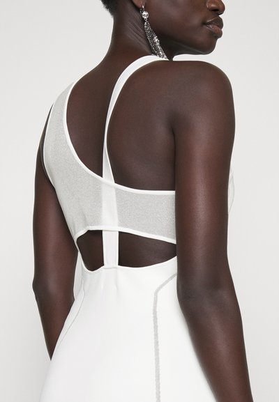 Abito bianco senza maniche con un pannello in rete luccicante sul retro, caratterizzato da ritagli orizzontali e verticali e dettagli di cucitura eleganti.