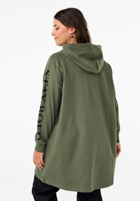Felpa verde oliva con una vestibilità rilassata, dotata di cappuccio, maniche lunghe e la scritta "STAY BOLD" stampata in nero sulla manica destra.