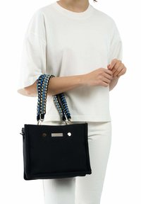 Zwarte stoffen handtas met decoratieve blauwe en beige gevlochten handvatten, voorzien van gouden hardware accenten en een strass-detail aan de voorkant.
