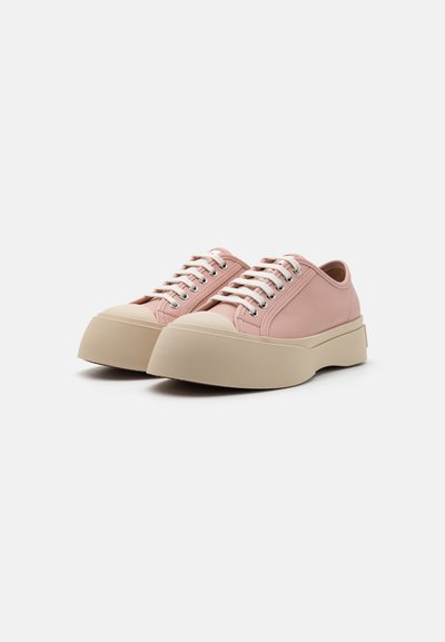 Rosa lädersportskor med en beige gummisula, rund tå och klassiska snören med silverfärgade öglor. Slät textur och minimalistisk design.