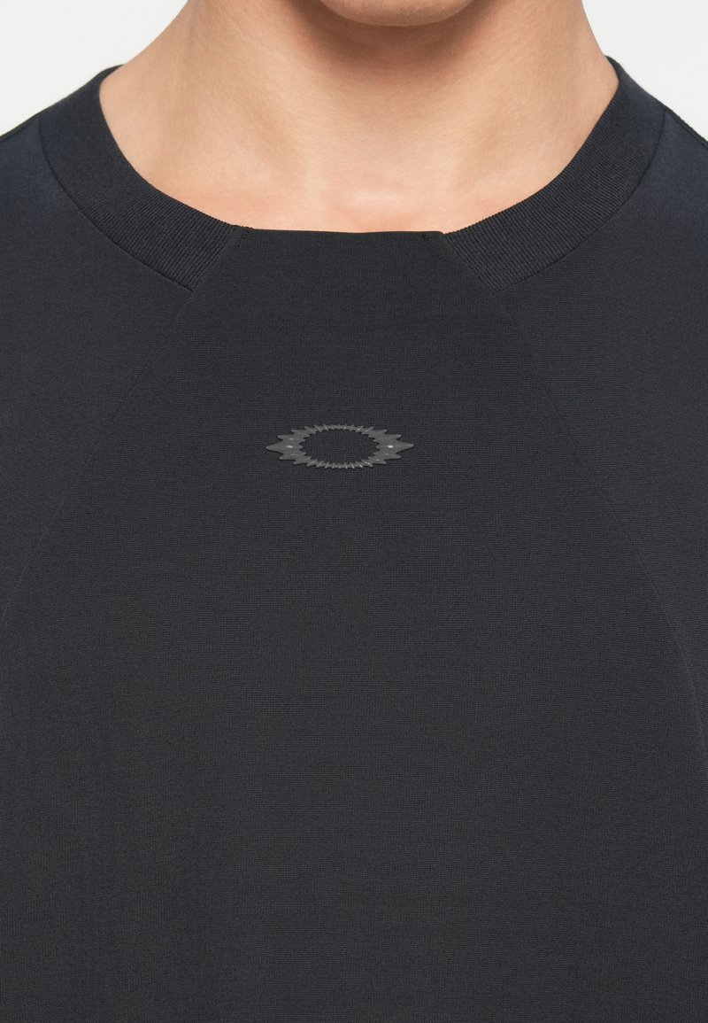 Camisa de manga corta en azul marino oscuro con cuello redondo. Presenta un pequeño logotipo tonal en el centro del pecho. Textura suave y lisa.