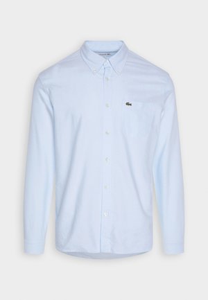 Hellblauses, langärmeliges Button-up-Hemd aus Baumwolle. Verfügt über einen spitzen Kragen, eine Tasche auf der linken Brust und ein kleines Logo.
