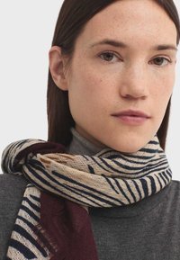 Buntgestreifter Schal in Creme und Marine mit einem strukturierten Abschnitt in Bordeaux. Leicht und schmiegt sich um den Hals.