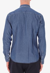 Camicia di denim blu medio, con colletto button-down, maniche lunghe e orlo curvo. Il tessuto ha una texture liscia con una leggera scoloritura.