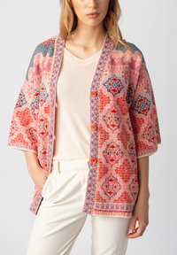 Spalvinga, raštuota kimono tipo striukė raudonos, rožinės ir mėlynos spalvų. Turinti trumpas rankoves, laisvą siluetą ir oranžinius mygtukus priekyje.