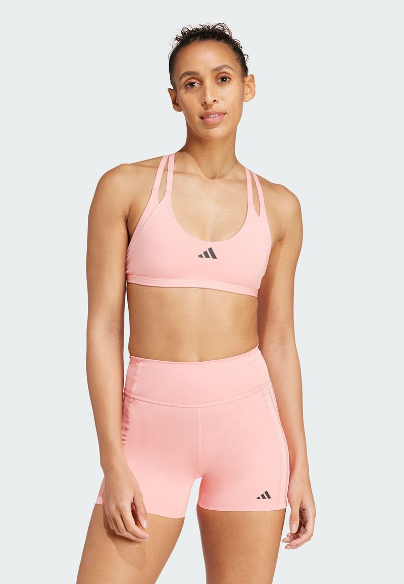 Lichtroze sportbeha en high-waisted shorts van soepel, rekbaar materiaal. Kenmerkt zich door zwarte logo-accenten en een multi-gestrengeld ontwerp.