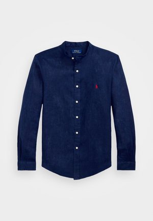 Marineblaue Leinenbluse mit Stehkragen, langen Ärmeln, Knopfverschluss und einem kleinen roten gestickten Logo auf der Brust.