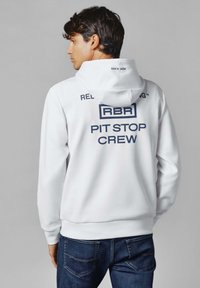 Biela mikina s kapucňou a modrým textom "RBR PIT STOP CREW" na chrbte, s priliehavým strihom a jemnou textúrou látky.