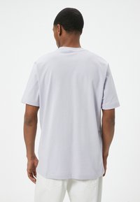Lyse lilla kortærmet T-shirt med rund halsudskæring, blødt stof og lige snit, som viser et minimalistisk design uden synlige mønstre.