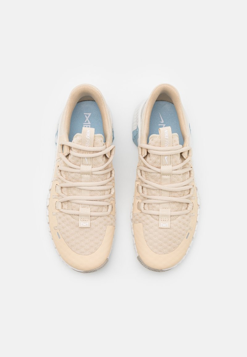 Paire de chaussures de course Nike beige avec tiges en mesh et lacets larges, vues de dessus sur fond blanc.
