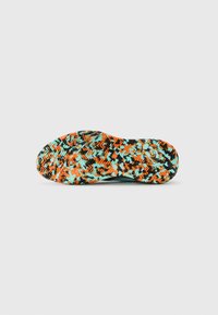 Sole of a shoe with multicolored orange, light blue, and black zigzag and textured tread pattern on a white background.