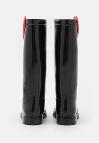 Svarta gummistövlar i knähöjd med en glänsande yta och röda dekorativa detaljer upptill, med en texturerad sula för bra grepp.