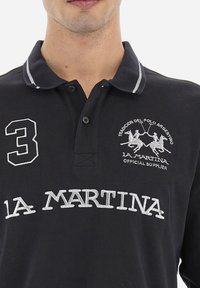 Czarna koszulka polo z szarymi akcentami, haftowane logo, numer 3 na lewej piersi oraz zapinany kołnierzyk. Wykonana z materiału bawełnianego.