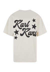 Kremfarget bomull T-skjorte med stor svart tekst "Karl Kani" og stjernegrafikk på baksiden. Korte ermer og rund hals.