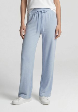 Person wearing light blue drawstring pants and white sneakers, standing against a plain light background.