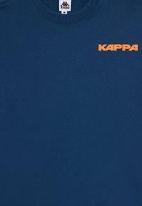 Mørkeblå bomulls t-skjorte med rund hals og oransje "KAPPA" logo på øvre venstre side. Glatt tekstur, kortermet.