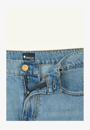 Primo piano di jeans in denim azzurro con cerniera parzialmente aperta, bottone in legno e etichetta in tessuto nero con la scritta "FAGUO DENIM".