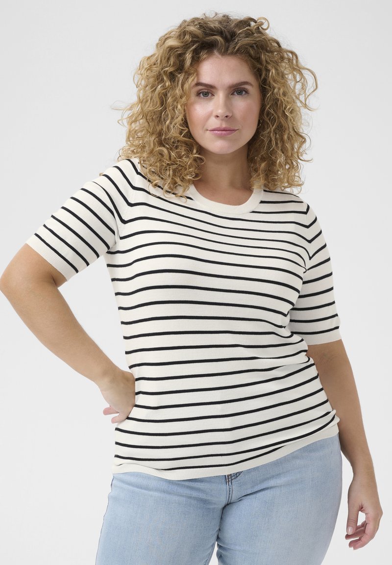 Tricou cu mânecă scurtă, cu dungi orizontale negre pe un fundal crem, având guler rotund și o textură moale. Este purtat cu blugi de culoare albastru deschis.