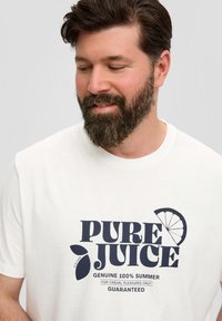 Witte katoenen T-shirt met een marineblauw grafisch ontwerp met de tekst "PURE JUICE" en een accent van een gesneden citroen. Korte mouwen, ronde halsontwerp.