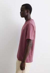 Camiseta de algodón burdeos de manga corta y cuello redondo, con un pequeño logotipo en el pecho y un diseño de corte relajado.