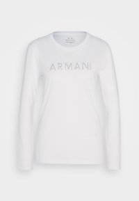Valkoinen pitkähihaiseksi T-paidaksi valmistettu puuvillasta, jossa on pyöreä kaulus, ja sen rinnassa lukee "ARMANI EXCHANGE" piikikkäillä hopeakirjaimilla.