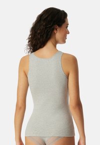 Grijze tanktop met een getailleerd ontwerp en brede bandjes, gemaakt van een zachte katoenmix. Opvallende fijne stiksels langs de randen.