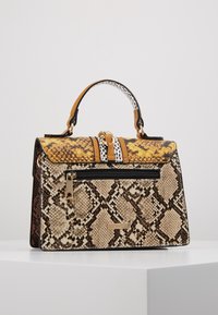 Rakennettu käsilaukku, jossa on keltainen ja musta käärmeennahkakuosi, kultaiset metalliosat ja vetoketjullinen tasku. Sisältää vastakkaisen kahvasuunnittelun.