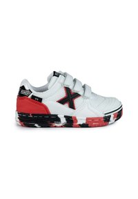 Zapatilla deportiva blanca con acentos en rojo y negro, parte superior de malla, tres correas de Velcro, suela de goma texturizada y diseño abstracto pintado en la suela.