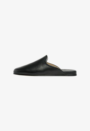 Mule en cuir noir à enfiler avec bout fermé arrondi et semelle plate, présentée de profil sur fond blanc.