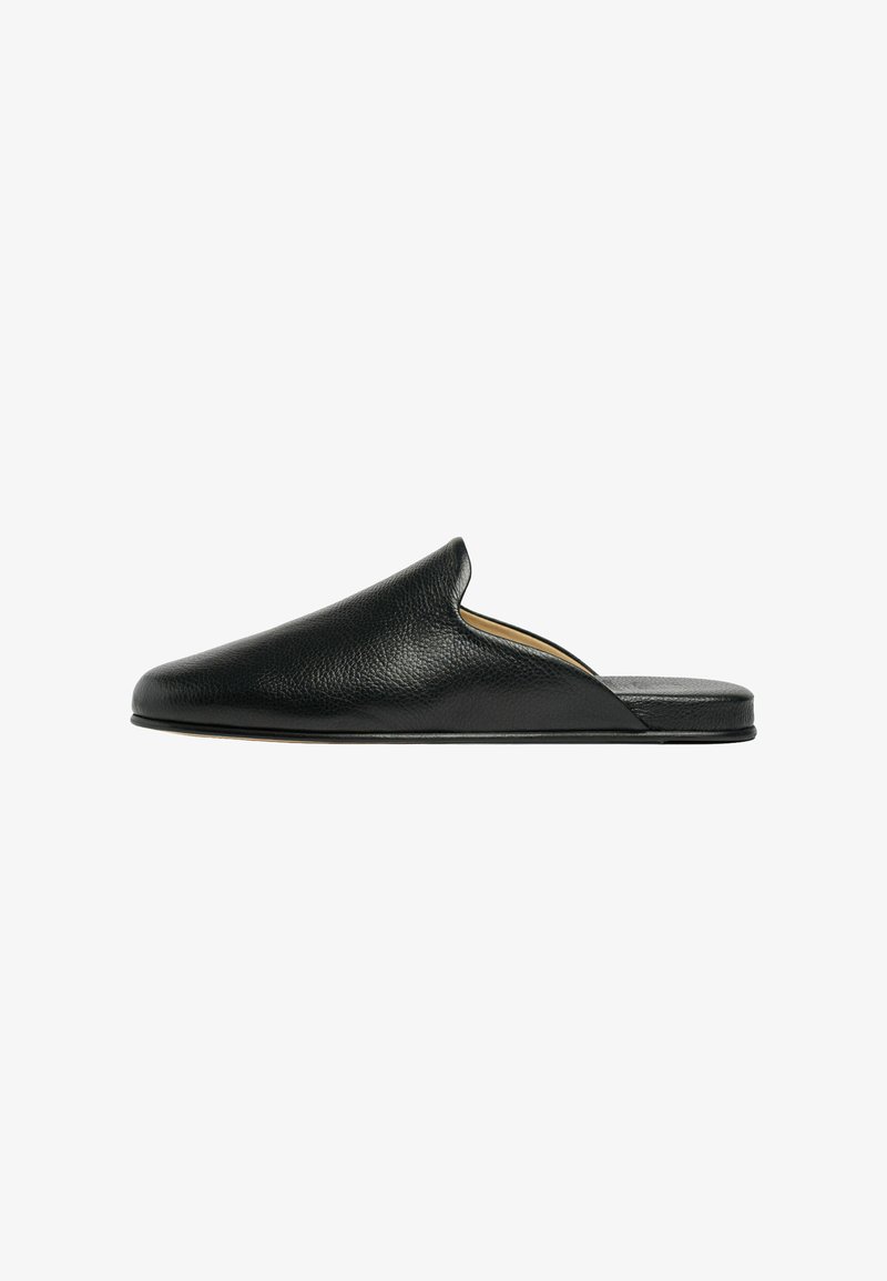 Mule en cuir noir à enfiler avec bout fermé arrondi et semelle plate, présentée de profil sur fond blanc.