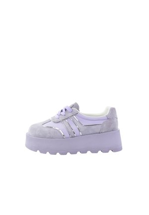 Gruba platforma sneakersów w jasnym fiolecie z zamszowymi i błyszczącymi paskami, wiązaniem na sznurówki oraz grubą podeszwą na białym tle.