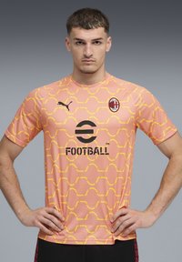 Rožinė futbolo marškinė su geltonu geometriniu raštu, su juodu logotipu ir PUMA prekės ženklu. Trumpomis rankovėmis, apvalia iškirpte.