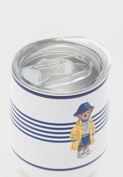 Λευκό μονωμένο ποτήρι με ναυτικές ρίγες και μια αρκούδα που φοράει κίτρινο αδιάβροχο, καπέλο και αθλητικά παπούτσια, με διάφανο πλαστικό καπάκι με αναδιπλούμενο στόμιο.