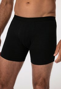 Černé bavlněné boxerky s měkkým elastickým pasem, na kterém je embosované jméno značky "JP1880". Hladká textura, těsně přiléhající střih.