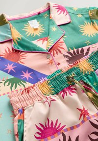 Buntes Pyjama-Set mit einem Hemd, das eine Knopfleiste und einen Kragen hat, kombiniert mit Shorts mit elastischem Bund. Hergestellt aus glattem Stoff mit Sonnen- und Sternmustern.