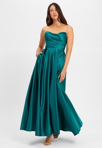 Robe sans bretelles, à longueur de sol en satin turquoise riche. Caractéristiques : corsage plissé, jupe fluide avec poches, et une texture lisse et brillante.