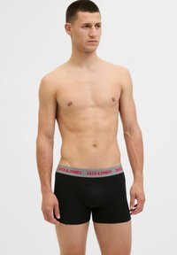 Schwarze Boxershorts aus Baumwolle mit einem grauen Bund, auf dem rot "JACK & JONES" steht. Enganliegendes Design, glatte Textur.