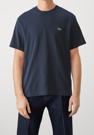 Marineblaues Baumwoll-T-Shirt, kurzärmelig, mit Rundhalsausschnitt, versehen mit einem kleinen grünen gestickten Logo auf der linken Brust. Legere Passform.